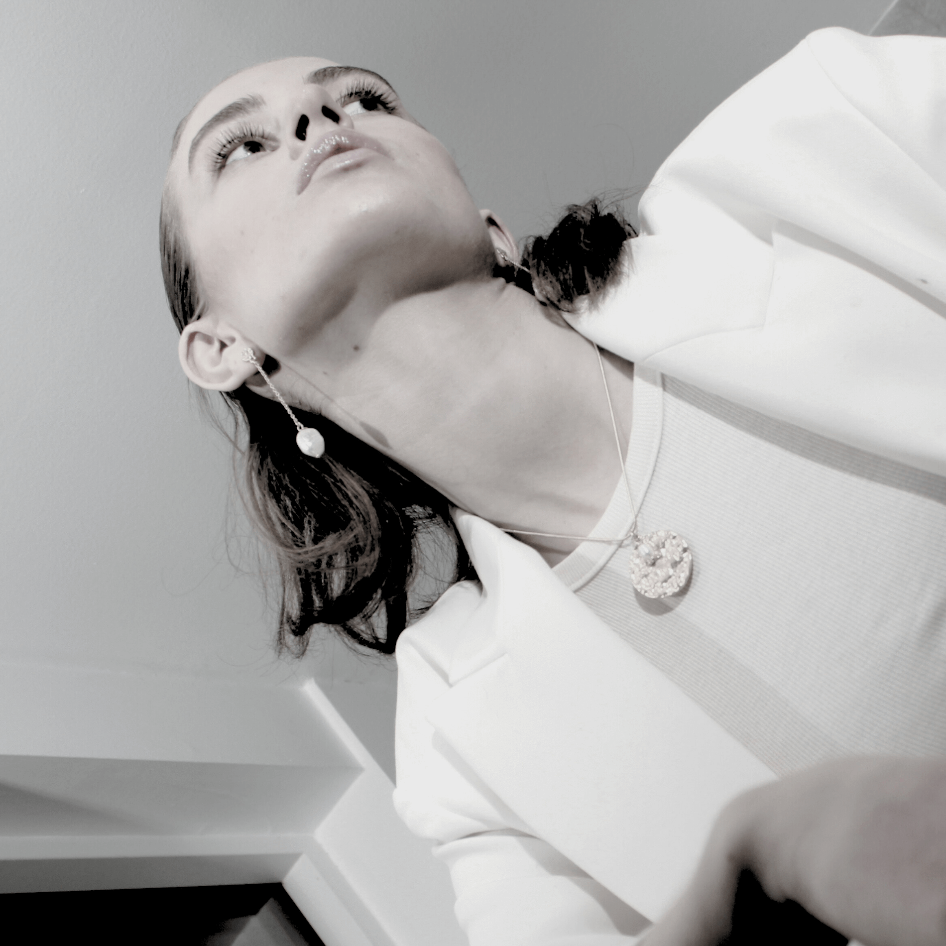 Black and white photo of a person wearing earrings and a necklace.