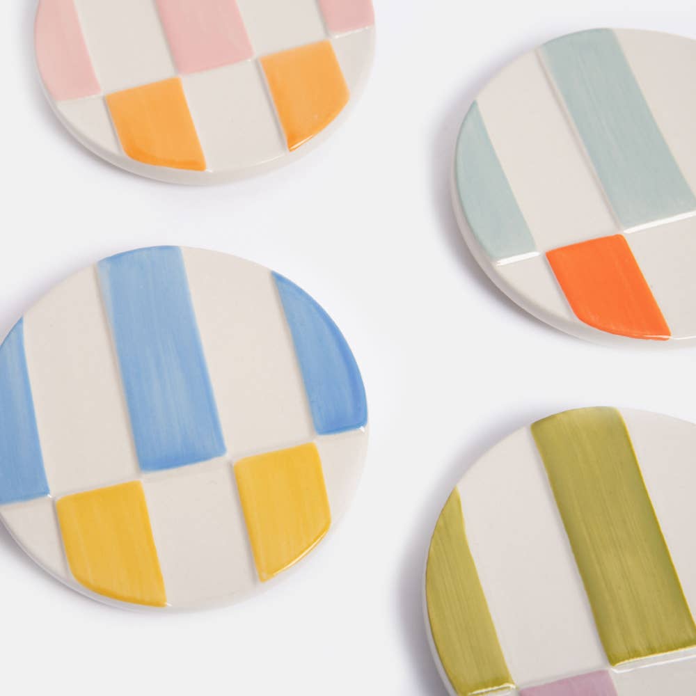 Set of four ceramic coasters with colorful geometric patterns on a white background