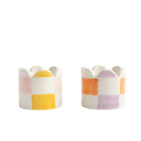 Two ceramic egg cups with colorful striped design on a white background