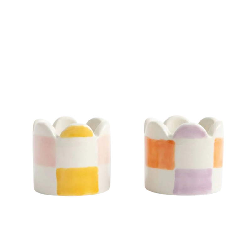 Two ceramic egg cups with colorful striped design on a white background