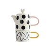 Ceramic teapot and mug set with black polka dots and heart designs on a white background