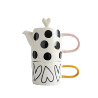 Ceramic teapot and mug set with black polka dots and heart designs on a white background
