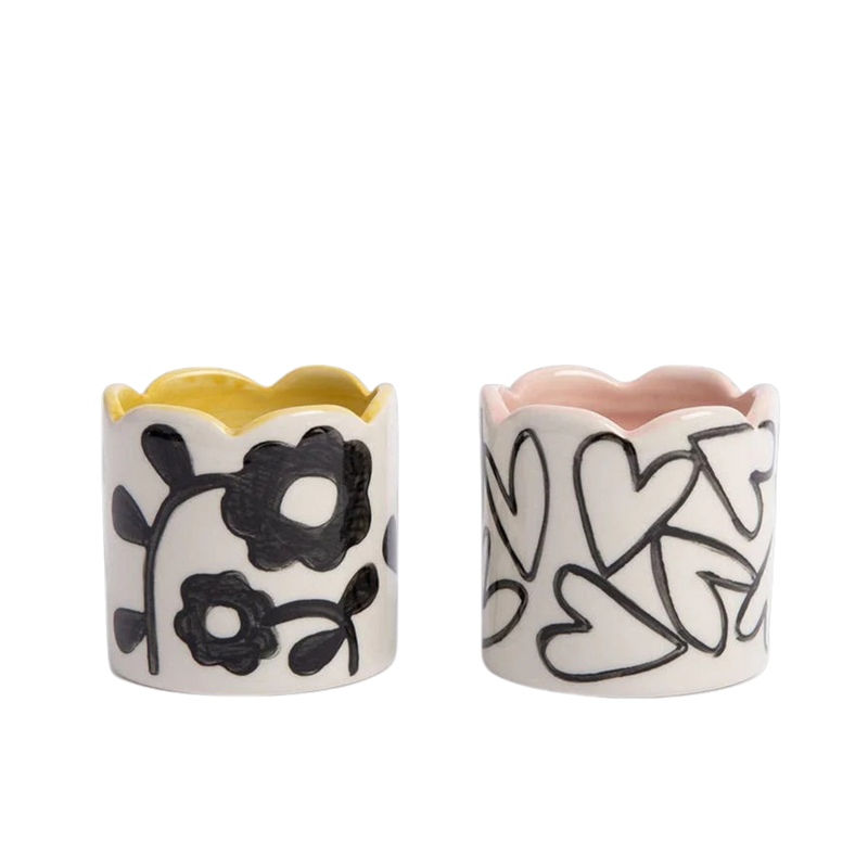 Two ceramic napkin rings with floral and heart designs on a white background