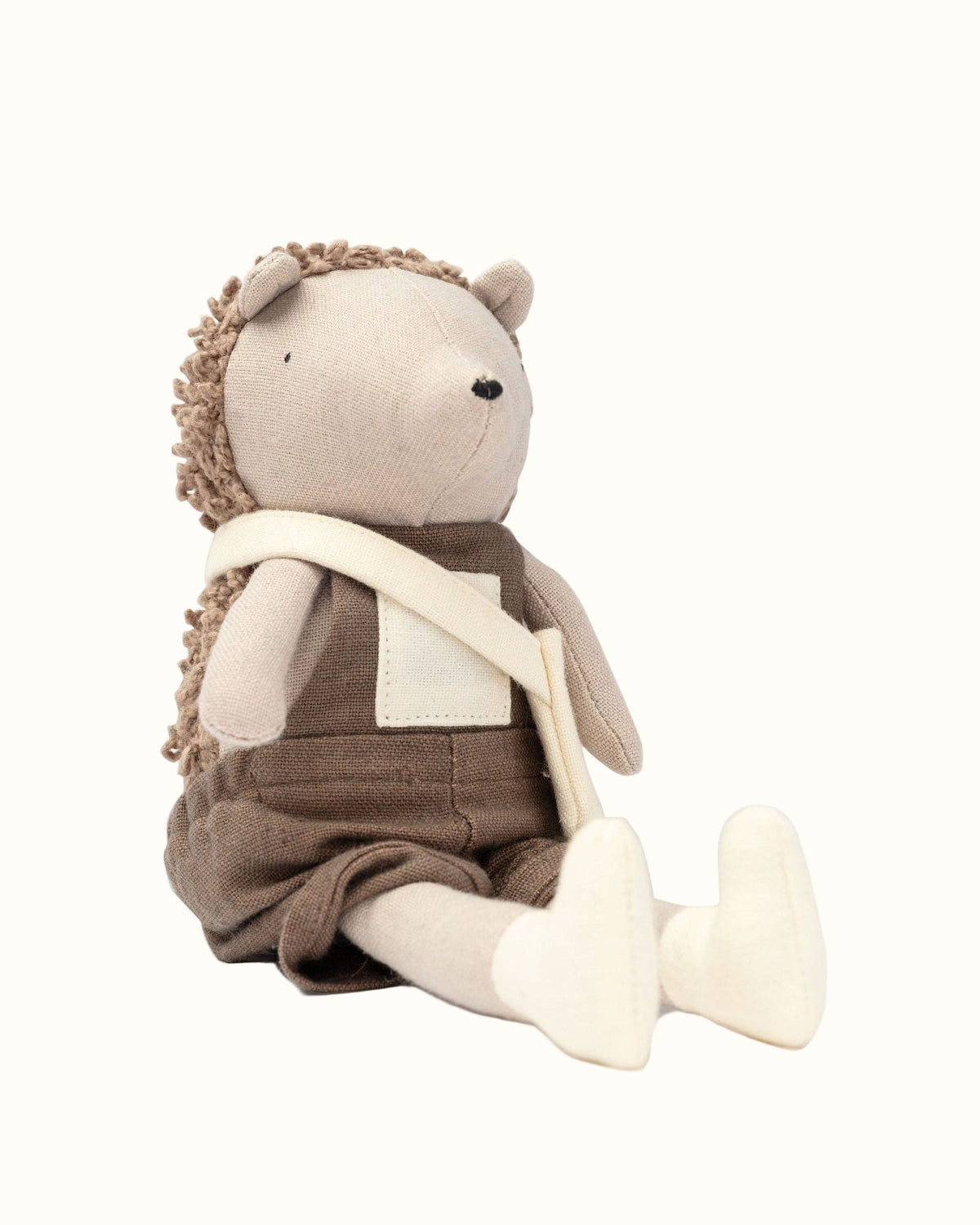 Stuffed toy resembling a bear in overalls on a white background