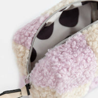Close-up of a polka dot pouch with pink textured fabric on a white background