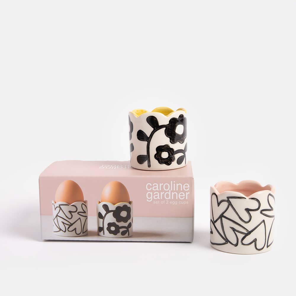 Set of ceramic egg cups with black floral design on a white background, featuring the brand 'caroline gardner'.