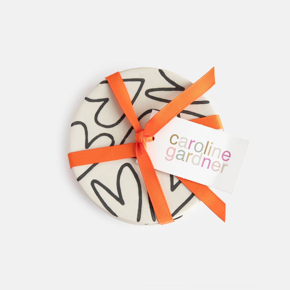 Decorative item with orange ribbon and 'Caroline Gardner' tag on a white background