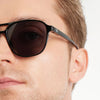 Close-up of a person wearing black sunglasses with a blurred background