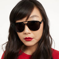 Woman wearing black sunglasses and red lipstick against a white background