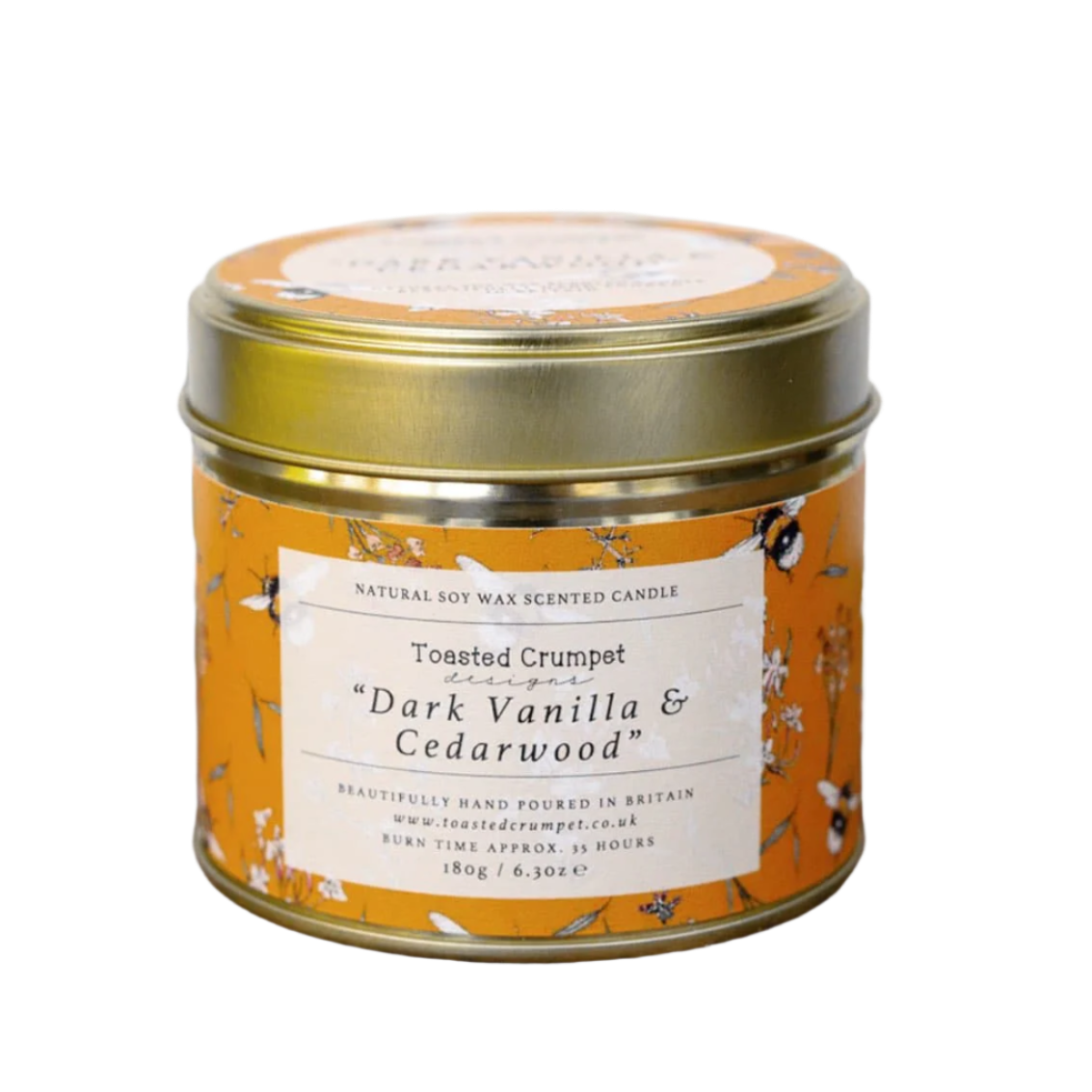Scented candle in a decorative tin with a label on a wooden surface.