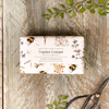 Bar of soap with floral and bee design packaging on a wooden surface