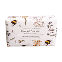 Bar of soap with floral and bee design packaging on a wooden surface