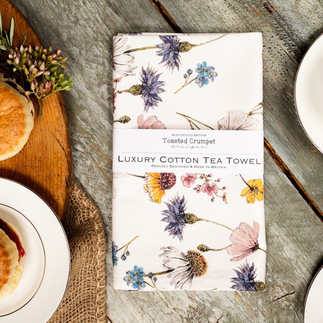 Floral patterned tea towel on a wooden table with pastries.