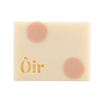 Bar of Oir Rose Geranium soap from the front on a white background. Beige bar, pink dot pattern and gold Oir logo.