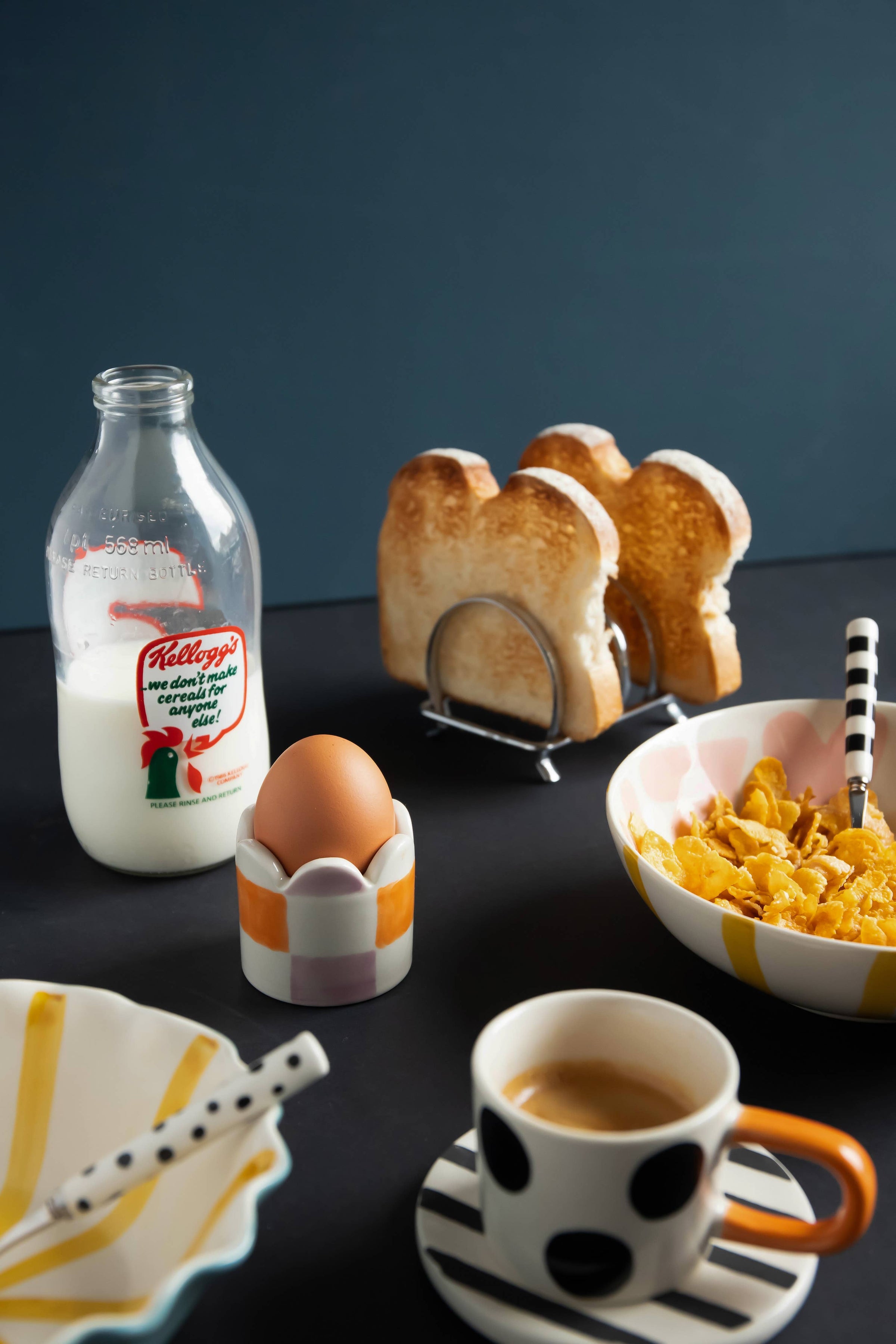 Breakfast setup with Kellogg's cereal, toast, and coffee on a dark surface.