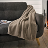 Brown blanket draped over a gray sofa with a fireplace in the background