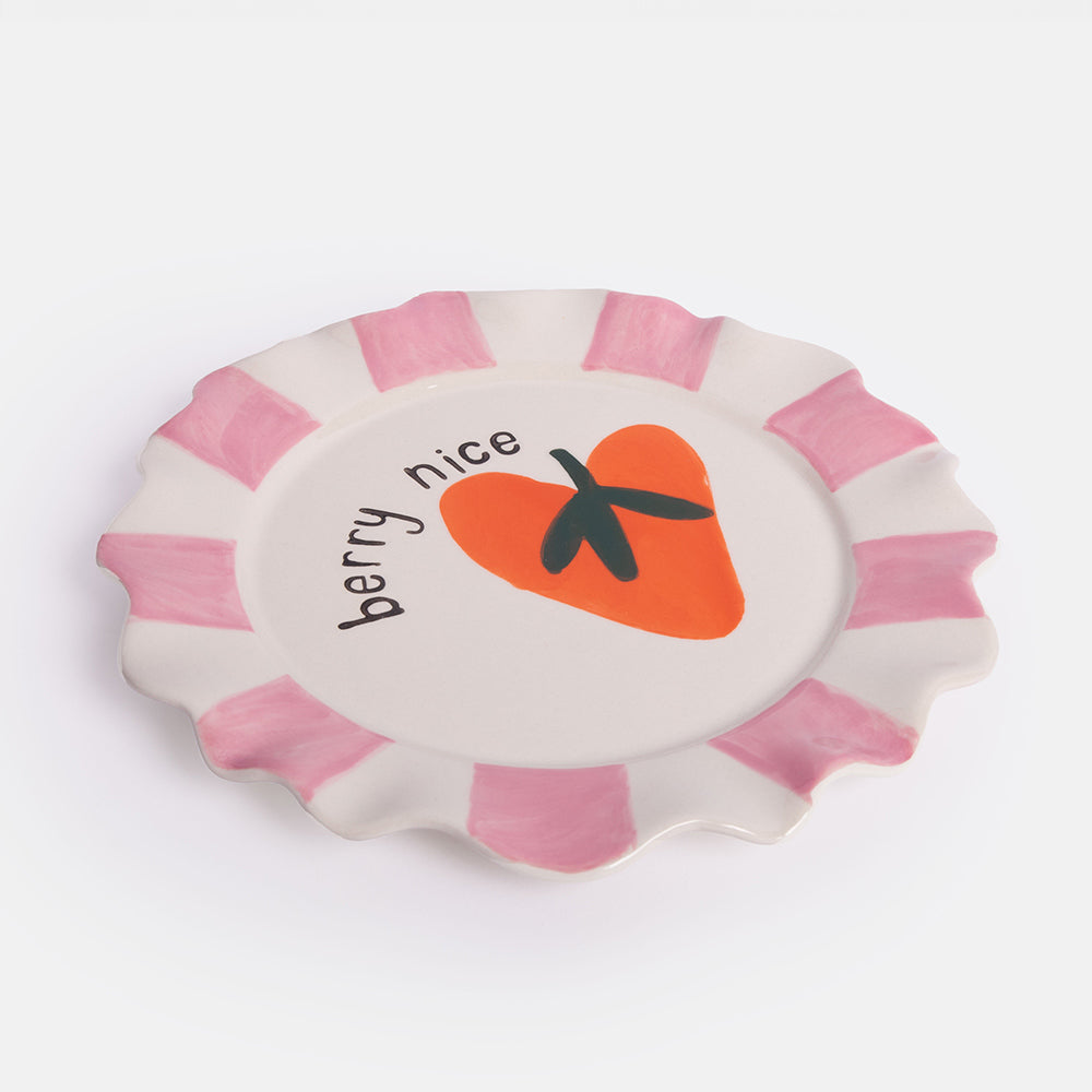 Round ceramic plate with pink rim, orange strawberry graphic, and 'berry nice' text on a white background