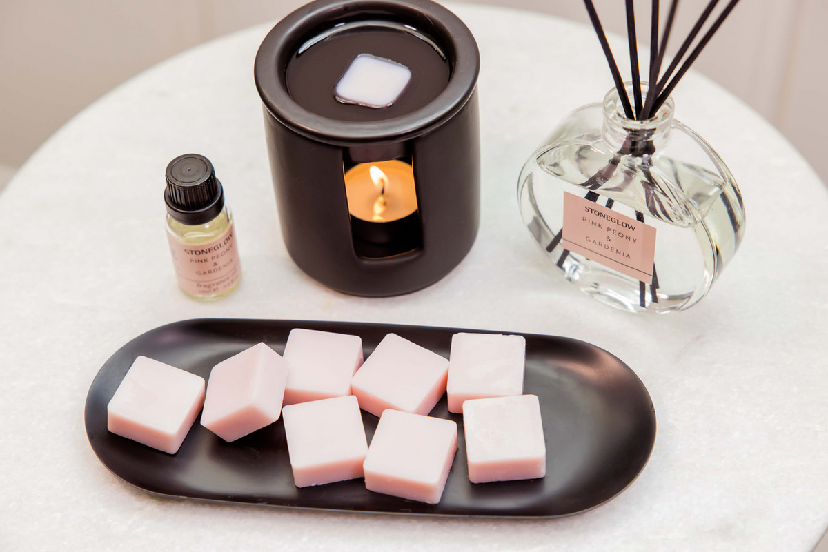 Aromatherapy setup with wax melts, diffuser, and essential oil on a white surface.
