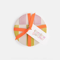 Round gift box with a colorful ribbon and 'caroline gardner' tag on a white background