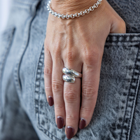 Hand wearing a silver ring with denim background