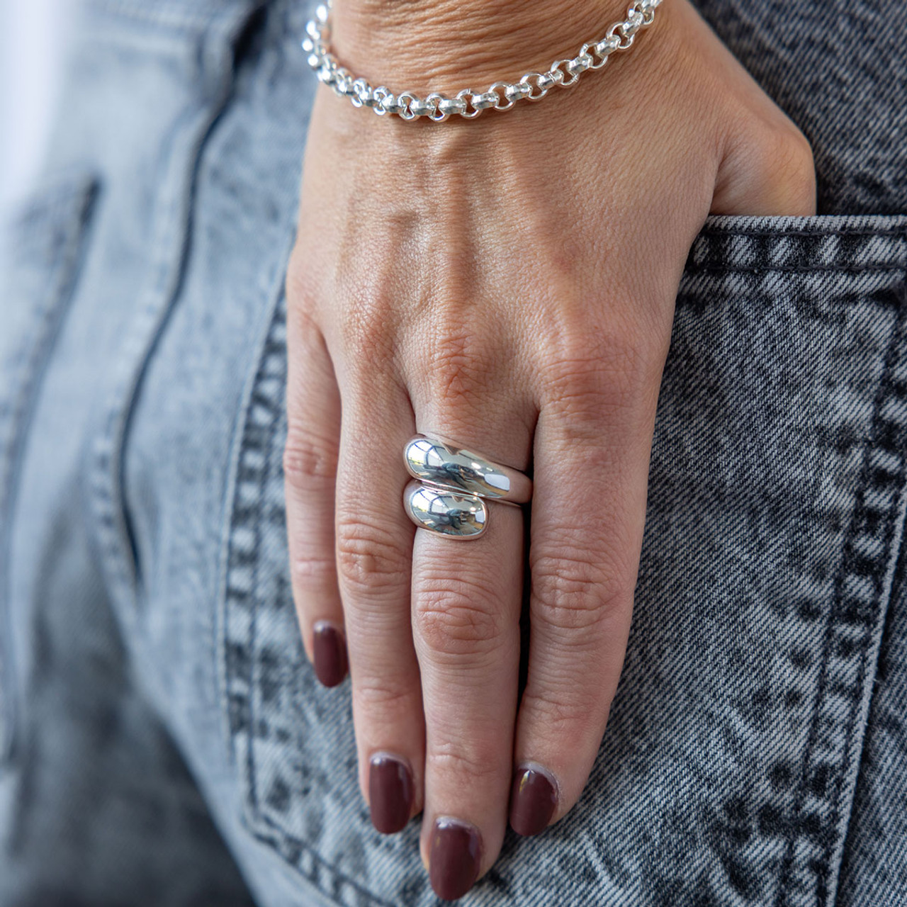 Hand wearing a silver ring with denim background