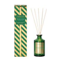 Green diffuser bottle with reeds and striped packaging on a white background