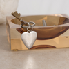 Silver heart-shaped keychain on a reflective surface