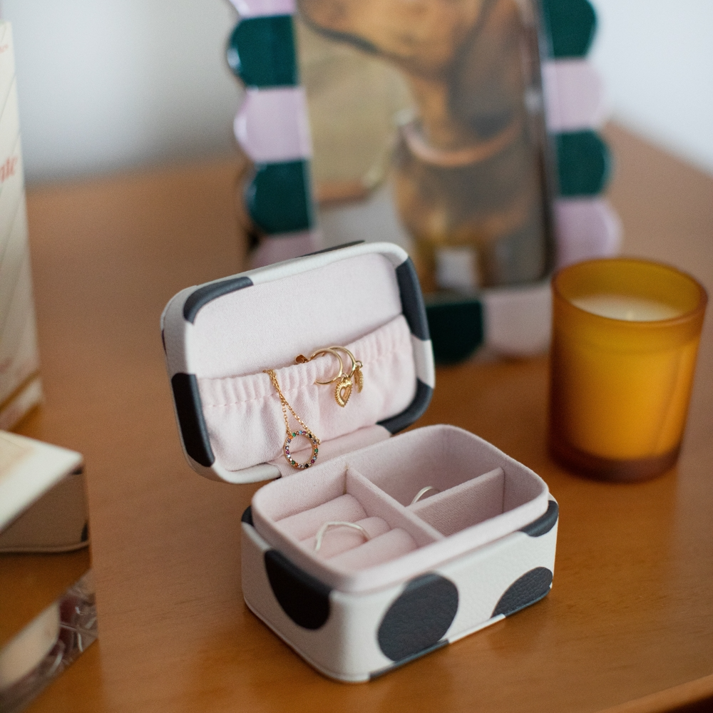 Polka dot jewelry box with rings on a wooden surface