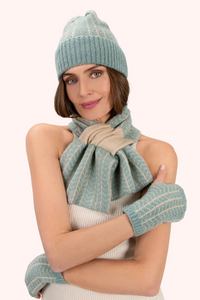 Woman wearing a matching teal knit hat, scarf, and gloves on a white background