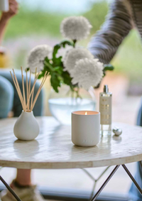 Candle and diffuser on a table with blurred background
