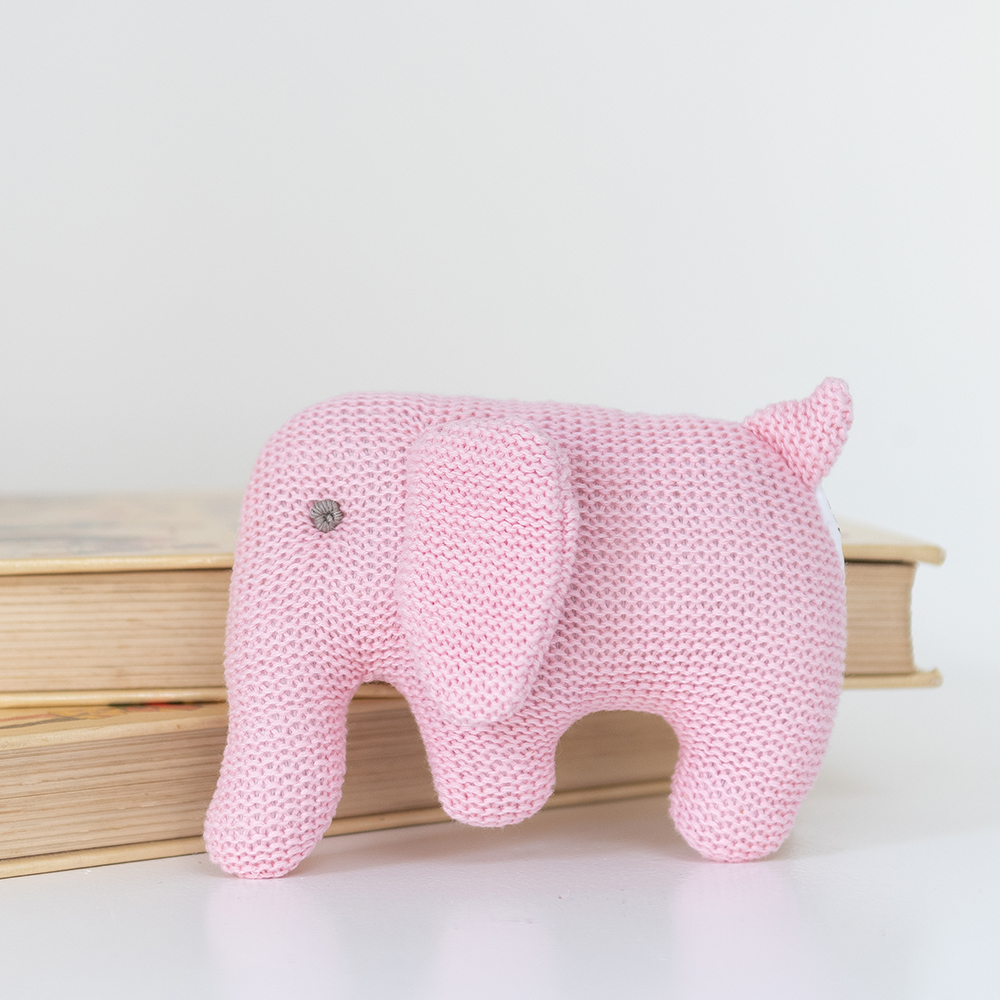 Pink knitted elephant toy on a light background