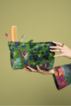 Floral-patterned pouch held by a person against a green background