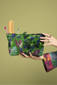 Floral-patterned pouch held by a person against a green background