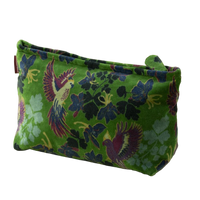 Green fabric pouch with floral and bird pattern on a yellow background