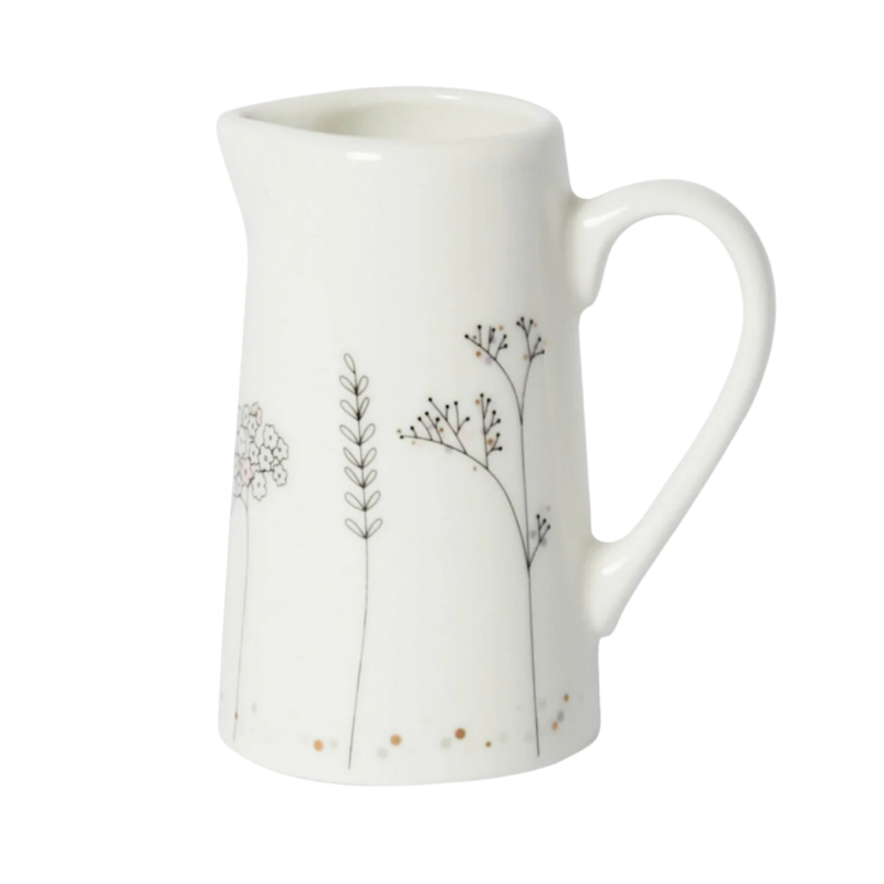 White ceramic pitcher with floral designs on a white background